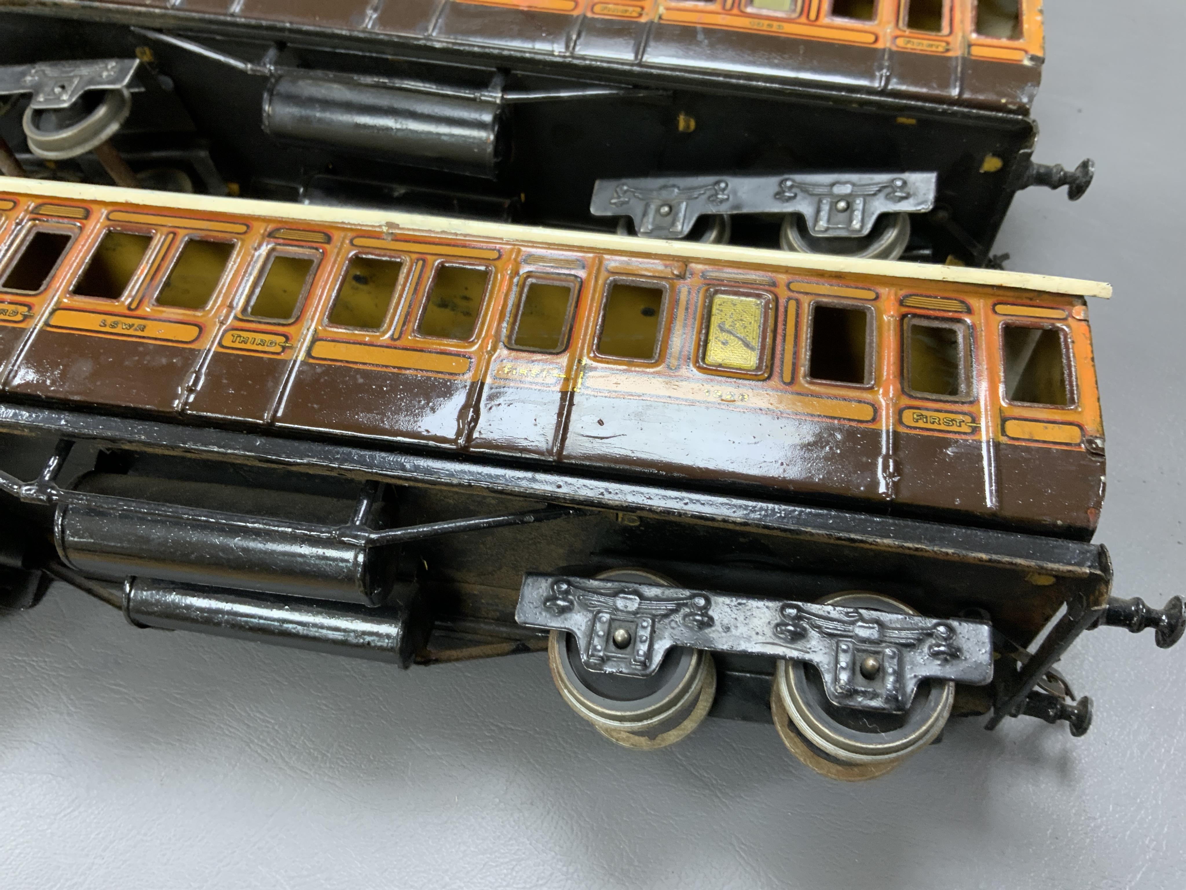 Three Carette for Bassett-Lowke 0 gauge railway 1921 series tinplate LSWR bogie coaches fitted with Bing couplings; two First Third Composite coaches, both 1328, and a full brake van, 133, all in salmon and chocolate liv